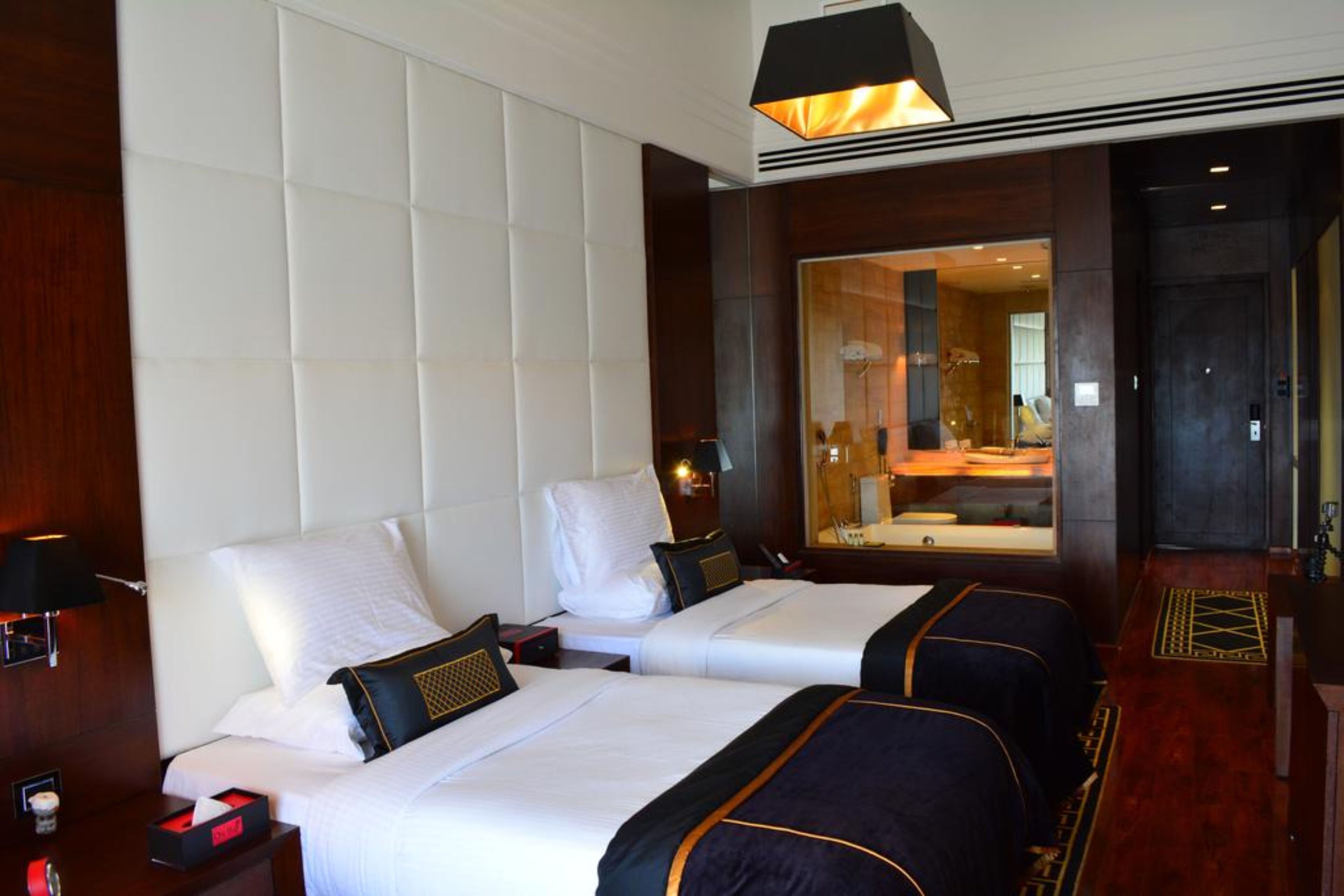 A hotel room with two beds, a large mirror, and a wooden floor.