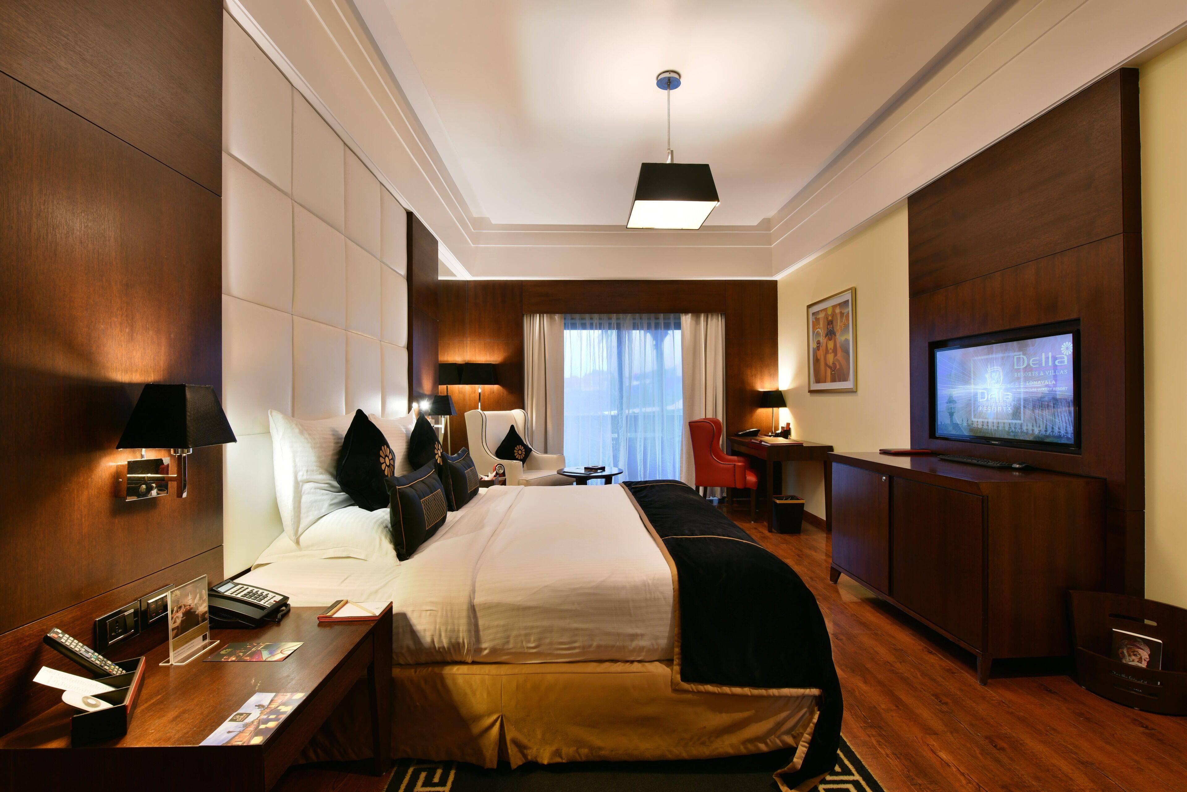 Habitación de hotel con una cama grande, mesitas de noche, un escritorio, un televisor y una ventana con cortinas.