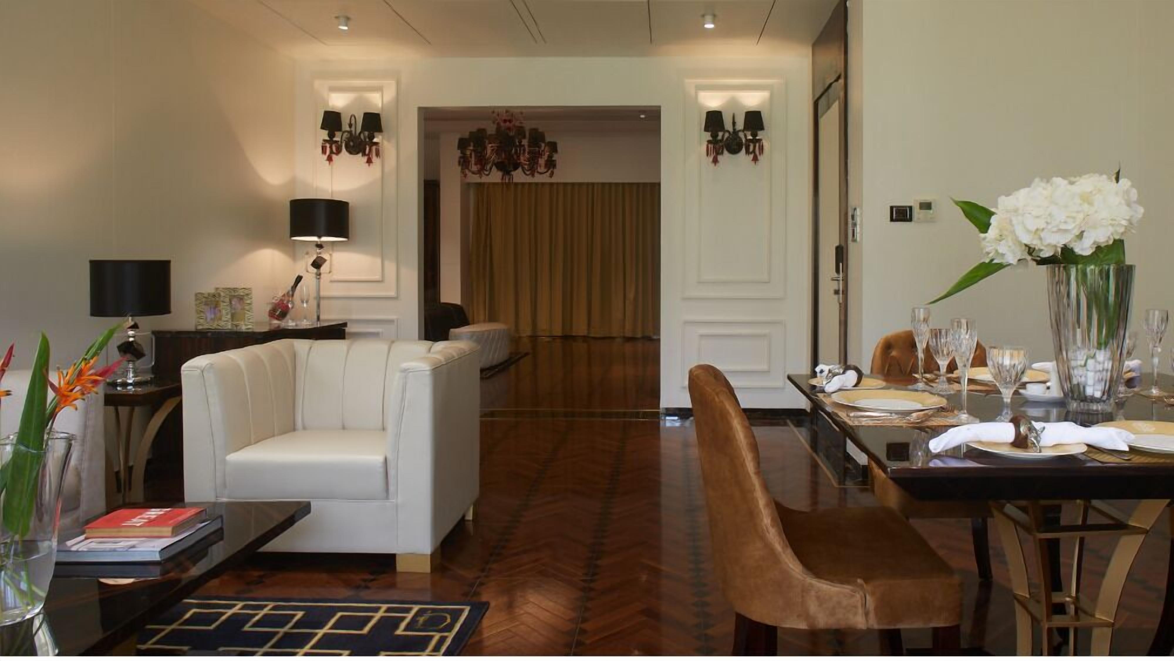 Une chambre d’hôtel moderne dotée d’un coin repas, d’un canapé, d’une table basse et d’un lustre.