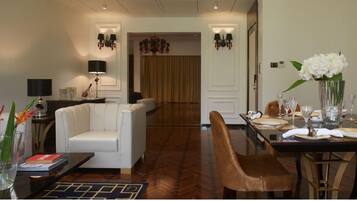 Une chambre d’hôtel moderne dotée d’un coin repas, d’un canapé, d’une table basse et d’un lustre.