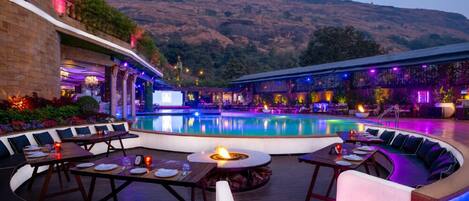A poolside area with a fire pit, seating, and a view of a hillside.
