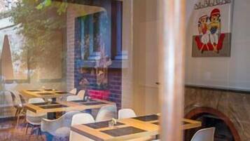 L’intérieur d’un restaurant, avec des tables et des chaises, un mur en briques et une fresque murale.