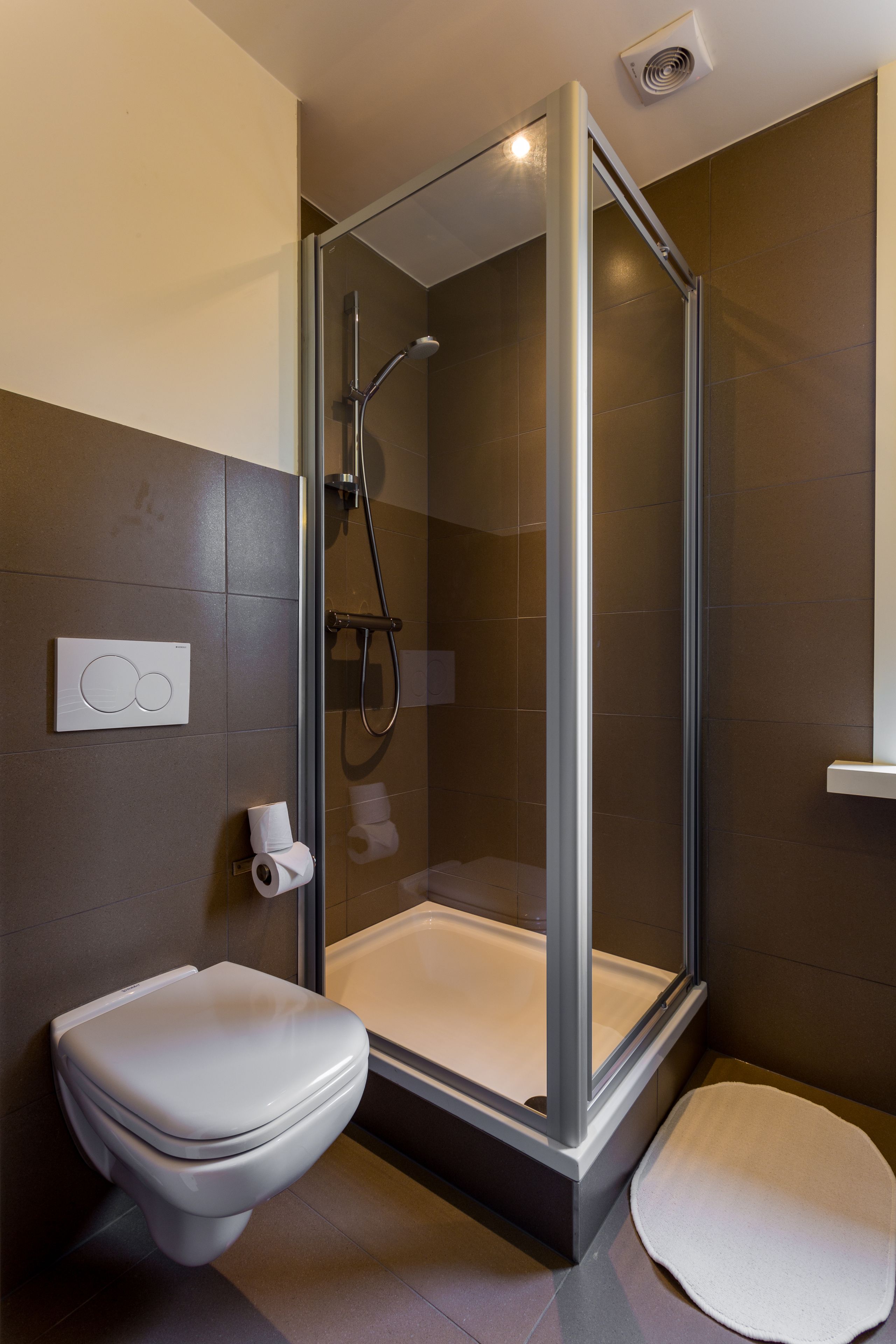 A modern bathroom with a glass-enclosed shower, a toilet, and a bathtub.