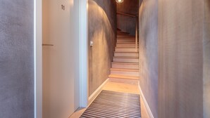 Un interior moderno con una escalera de madera, una puerta con número y un aplique de techo.