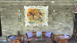 Una habitación con pared de piedra, un conjunto de sofás, una mesa redonda y dos adornos en la pared.
