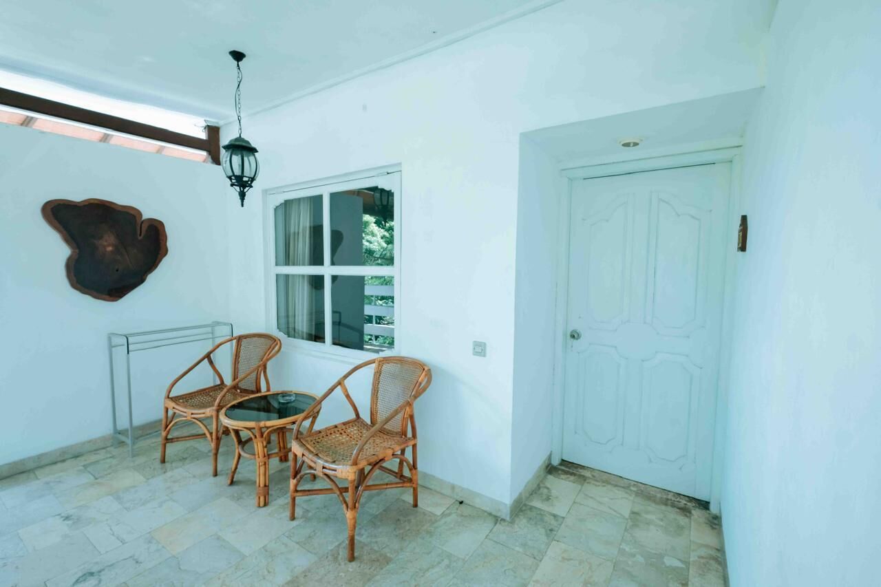 A room with a white door, a window, and two wicker chairs.