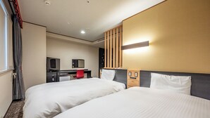 Ein Hotelzimmer mit zwei Betten, einem Schreibtisch mit Computer, einem Fernseher und einer Wandleuchte.