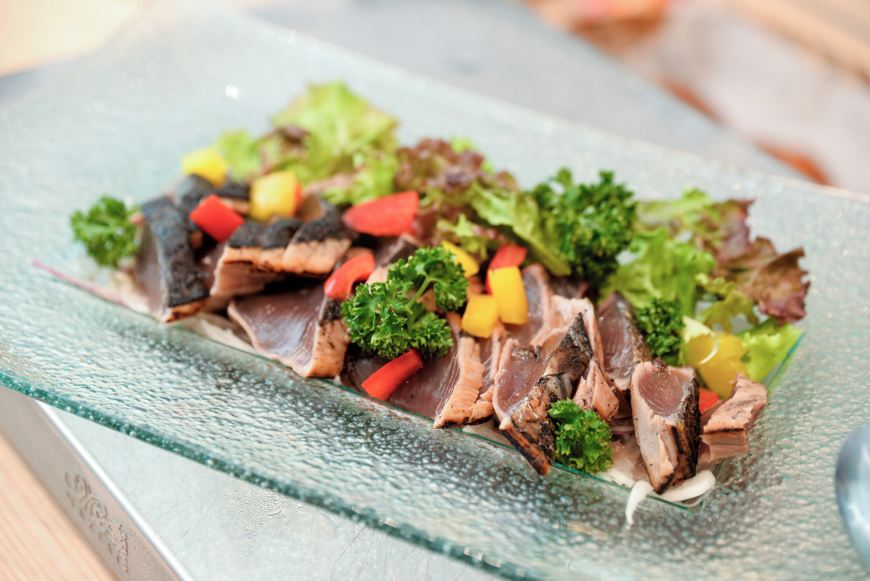A glass plate with sliced meat and vegetables.