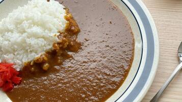 A plate with white rice and a brown sauce, possibly curry, on a table.
