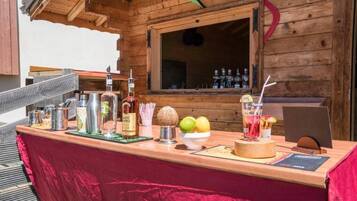 Zona de bar con barra de madera, mantel rojo, botellas de whisky Saint James, un frutero y un atril para el menú.