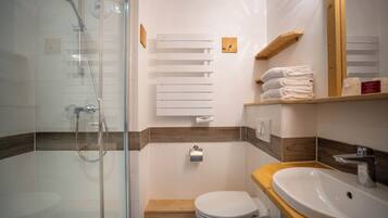 A modern bathroom with a glass-enclosed shower, a wooden vanity, and a white toilet.