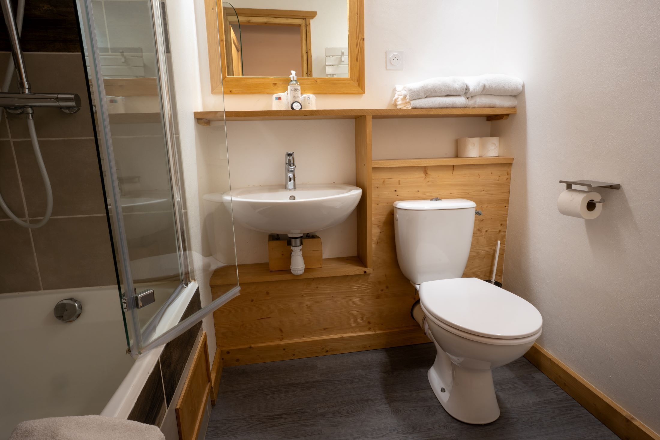 A compact bathroom with a glass shower enclosure, a white sink, and a toilet.