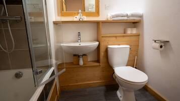 A compact bathroom with a glass shower enclosure, a white sink, and a toilet.
