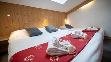 Un dormitorio con dos camas, paneles de madera en las paredes, un tragaluz y toallas sobre las camas.