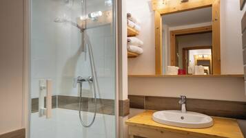 A bathroom with a glass-enclosed shower, a wooden vanity with a sink, and a mirror above the vanity.