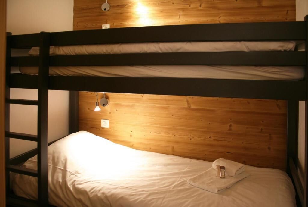 Una cama litera con cabecera de madera y una cama individual debajo.