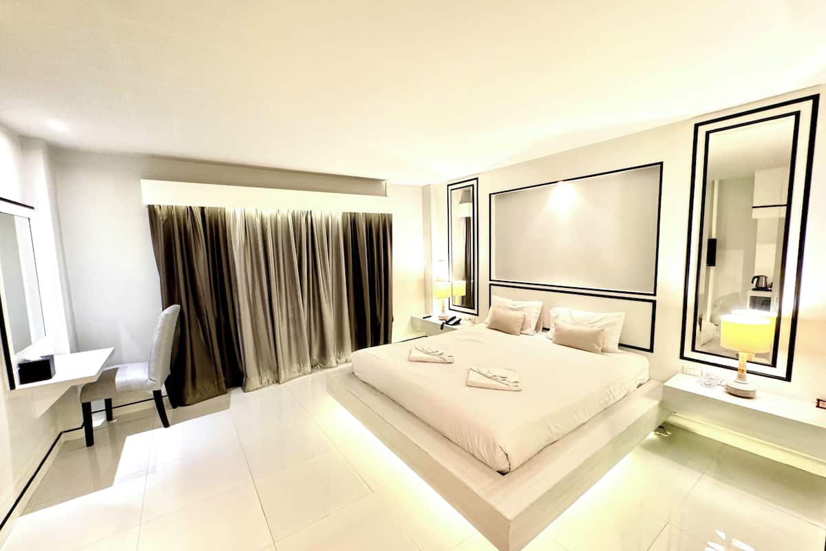 A modern hotel room with a large bed, a desk, and a chair.