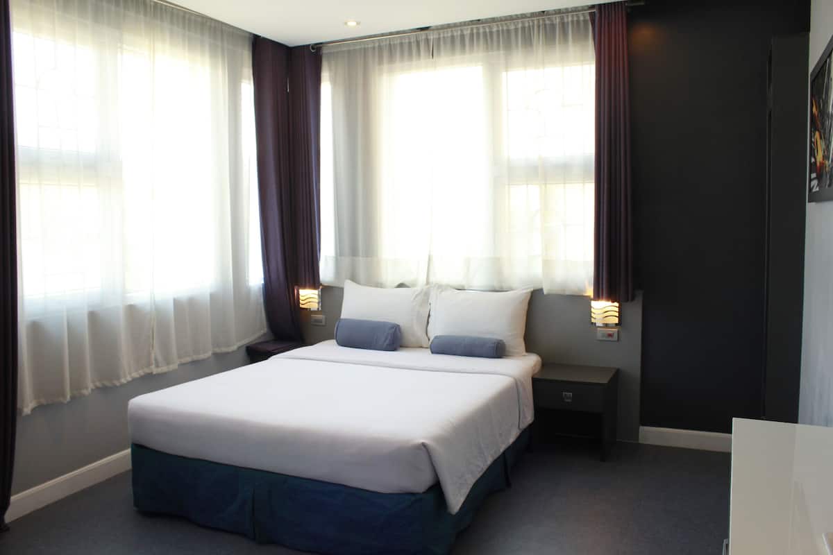 A hotel room with a large bed, two bedside tables, and a nightstand.