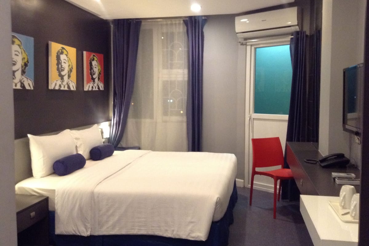 A hotel room with a bed, a desk, a chair, and a TV.