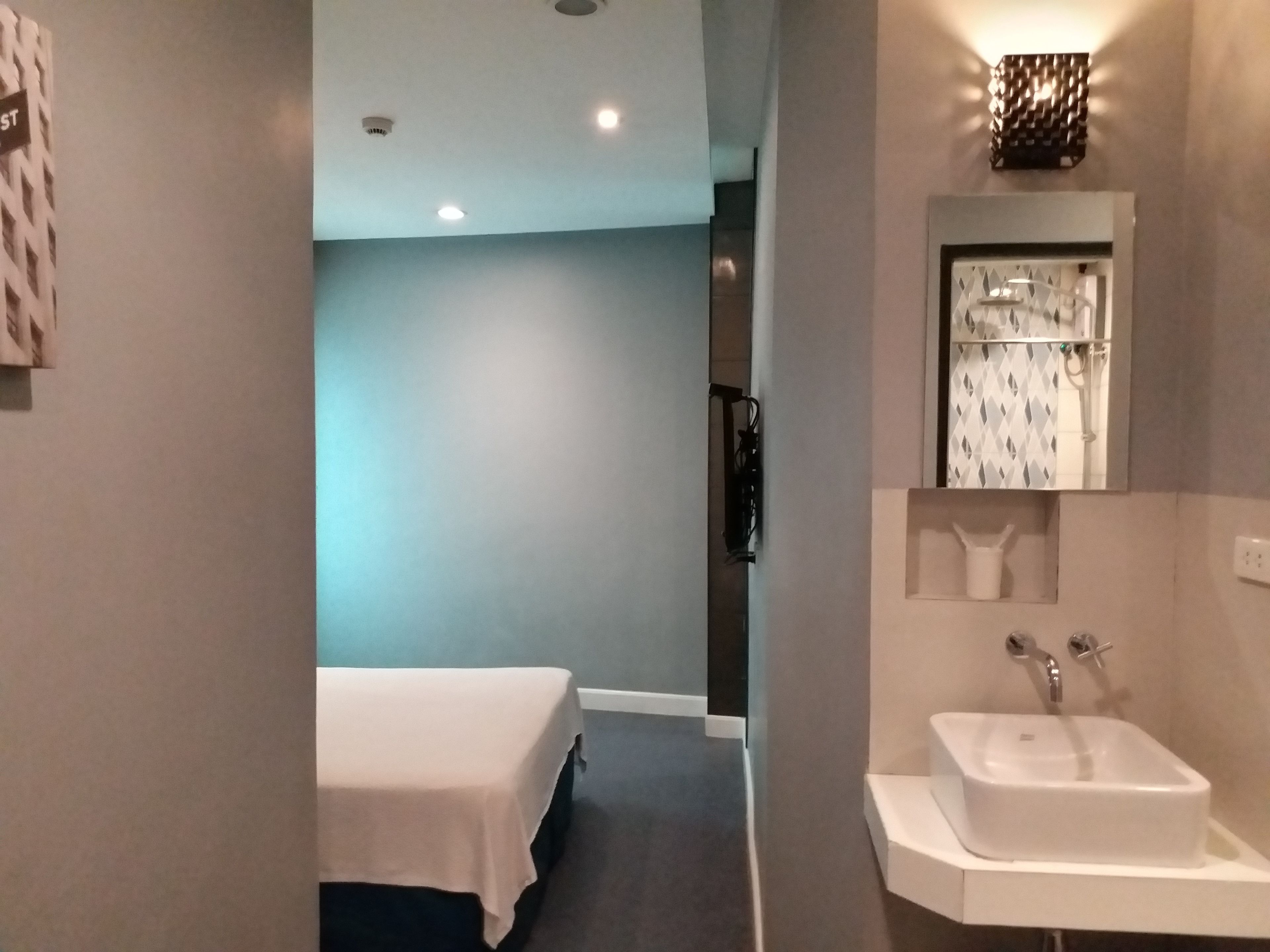 Une chambre d’hôtel avec un lit, un lavabo et un miroir.