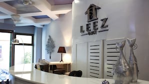 A hotel reception area with a modern design, featuring a reception desk, a lamp, decorative vases, and a sign with the hotel name. - Leez Inn Malate (Manila)