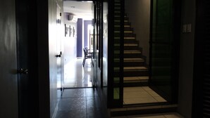 A modern hallway with a glass door leading to a staircase. - Leez Inn Malate (Manila)