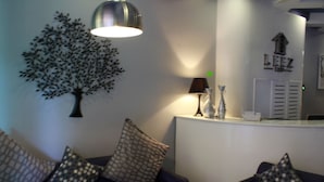 A reception area with a modern design, including a tree wall art, a lamp, and a reception desk. - Leez Inn Malate (Manila)