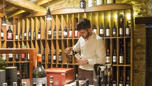 A wine cellar with wooden shelves stocked with various bottles and glasses. - Borgo san Benedetto (Montaione)