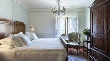 Un dormitorio con una cama grande, un armario de madera, una silla y una araña.