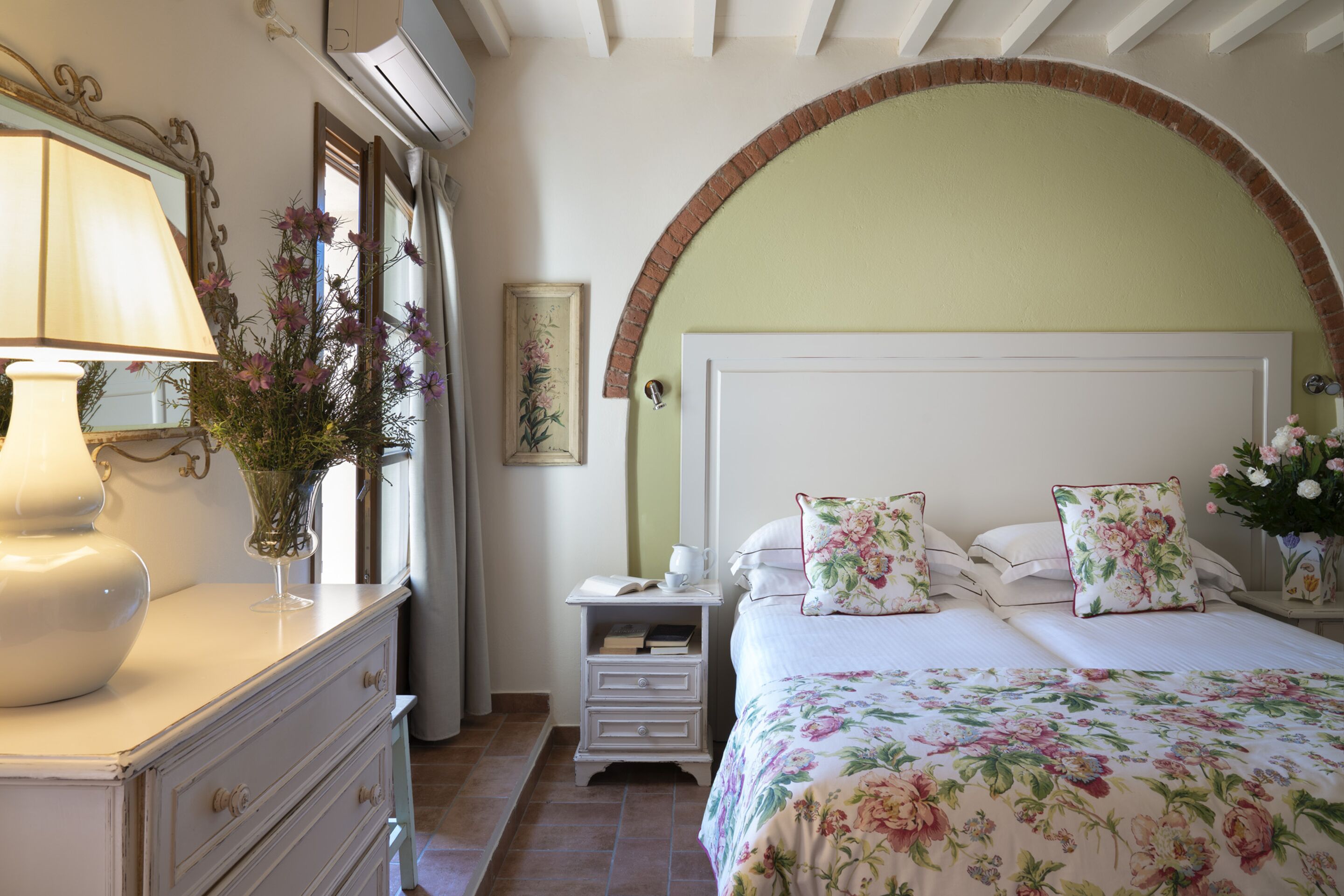 A bedroom with a bed, nightstand, dresser, and a lamp.