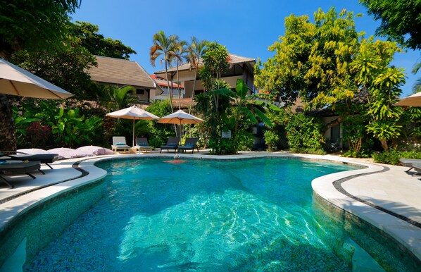 Alberca al aire libre, sombrillas en la alberca y camastros