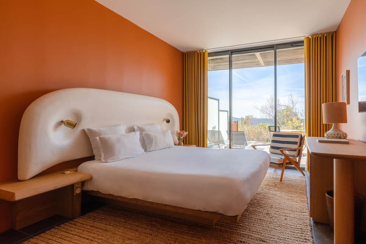 A modern hotel room with a large bed, a desk, and a chair.