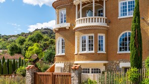 Une maison à deux étages avec une façade en pierre, de nombreuses fenêtres et un balcon.