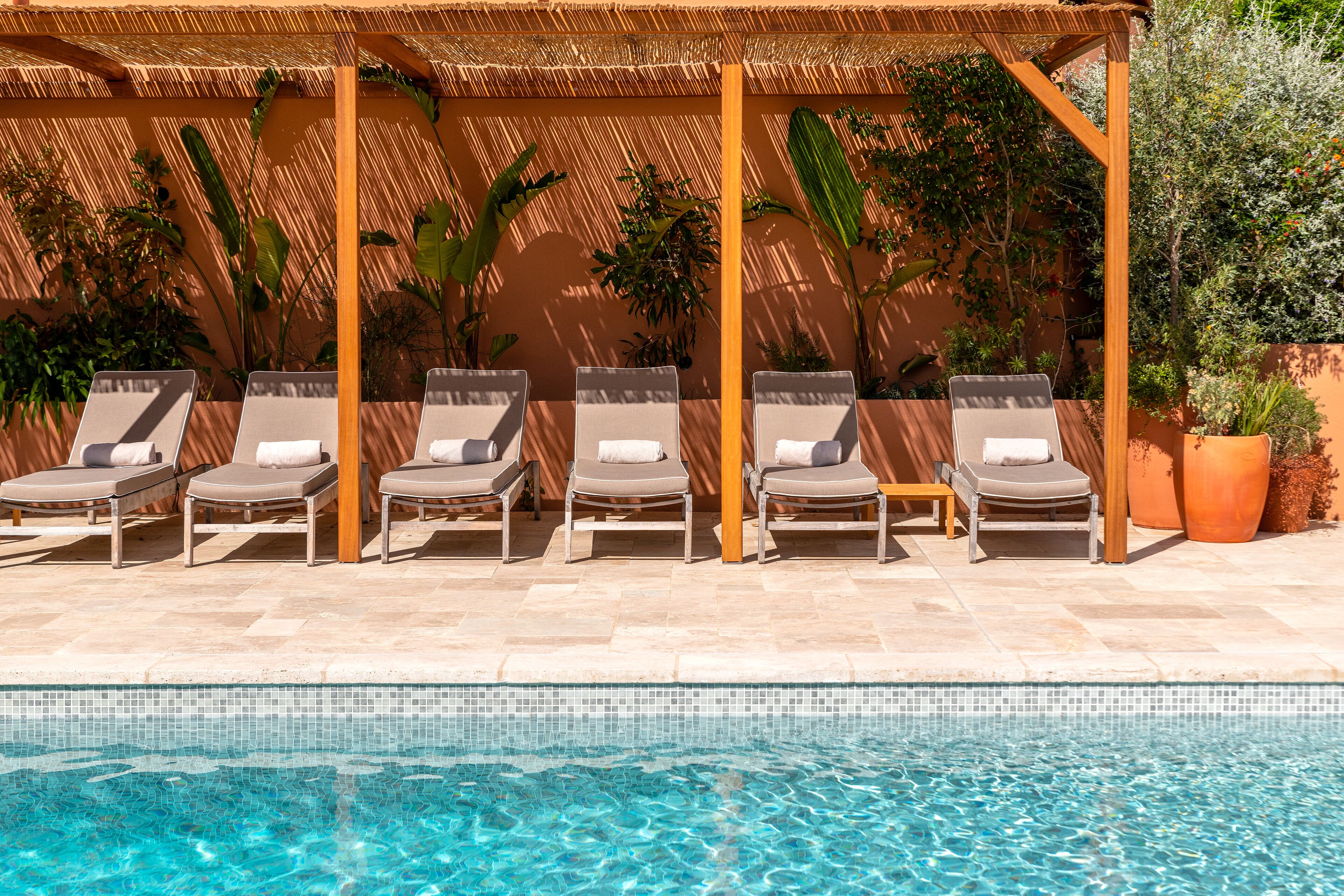 A poolside area with lounge chairs and a pergola.