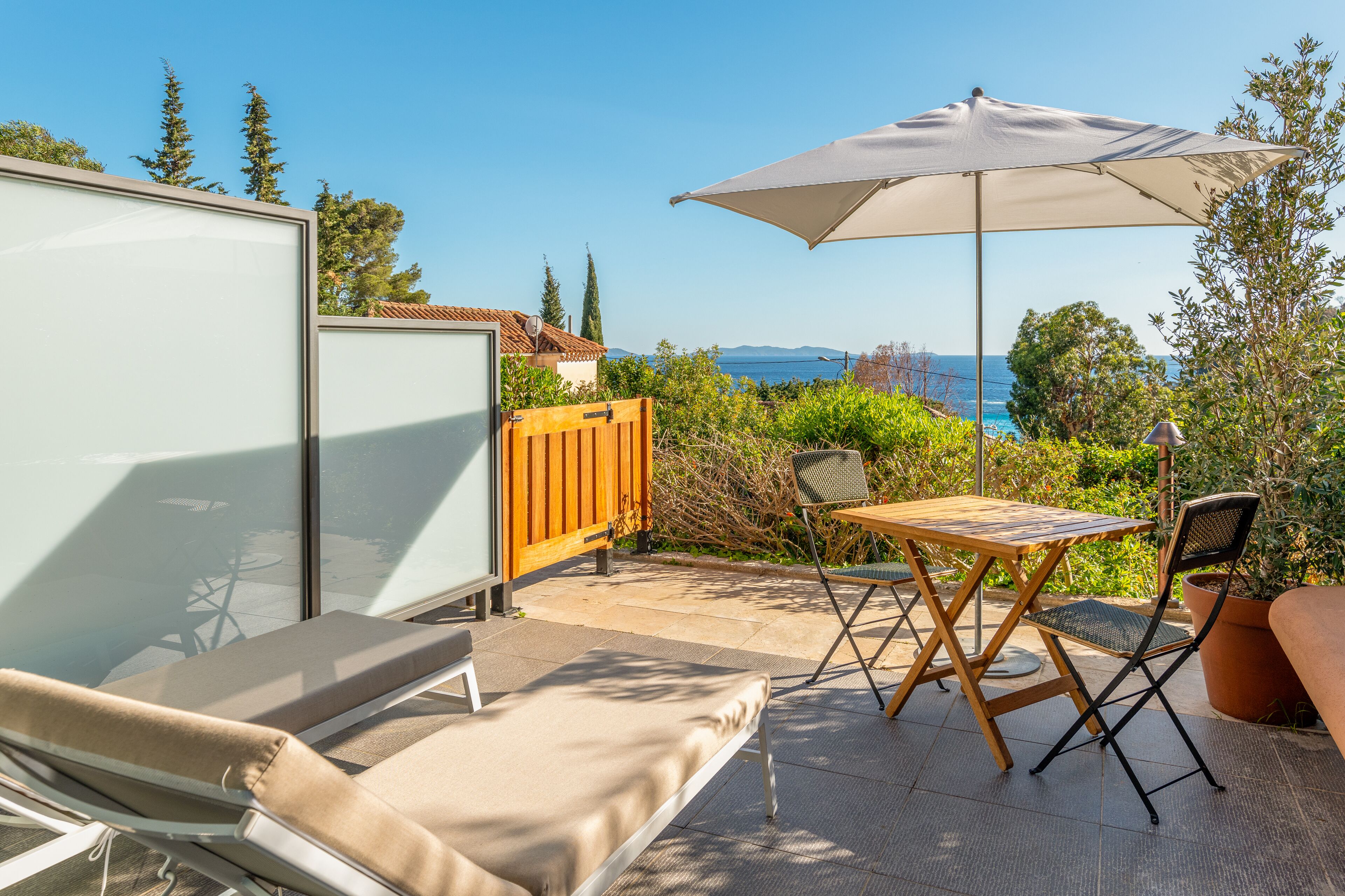 A balcony with a table, chairs, and an umbrella.