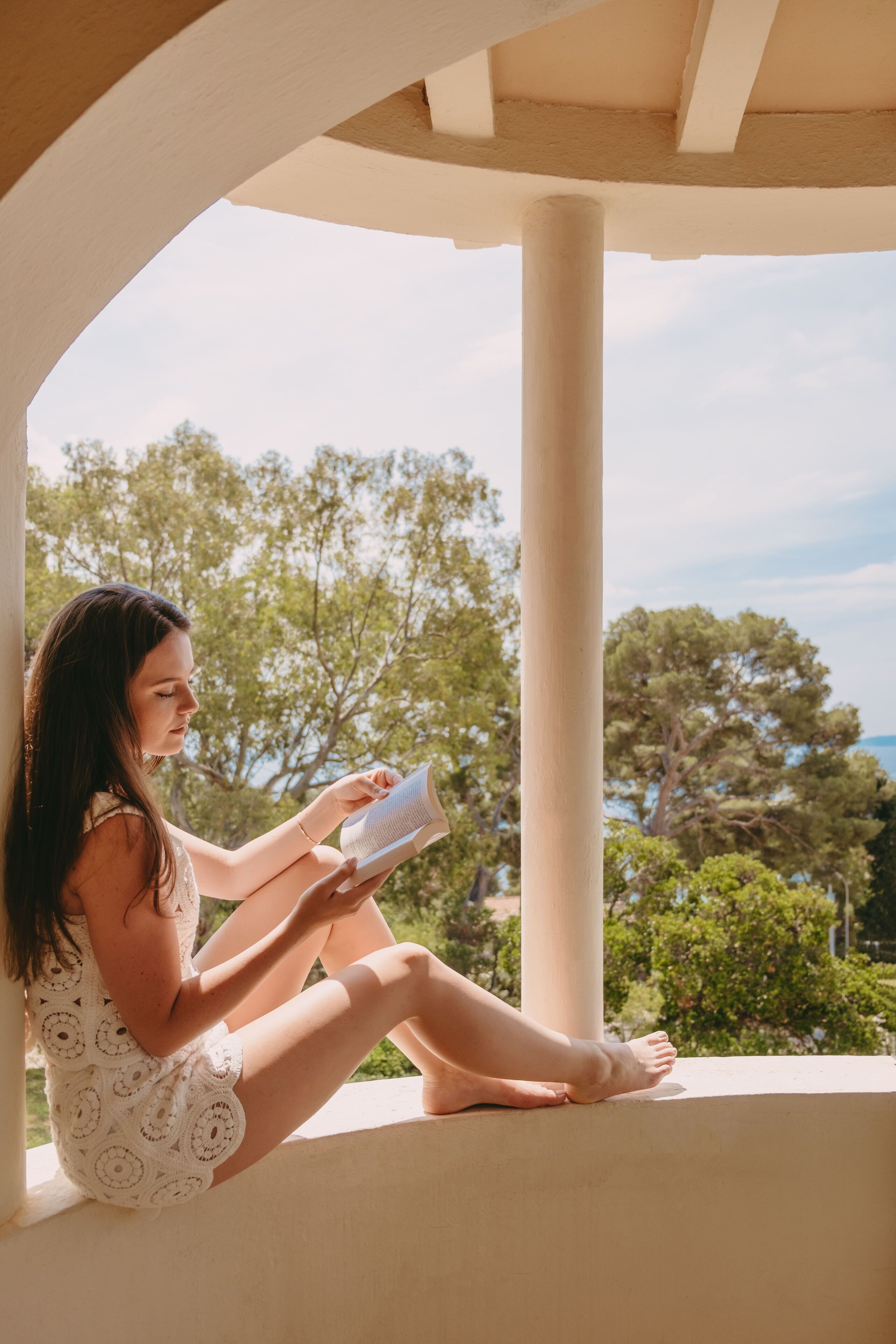 Una persona sentada en un balcón leyendo un libro.