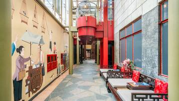 A corridor with a mural, red pillars, and seating areas.