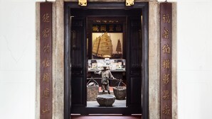 Een traditionele Chinese architectonische entree met een houten deur, decoratieve panelen en een verzameling culturele objecten.