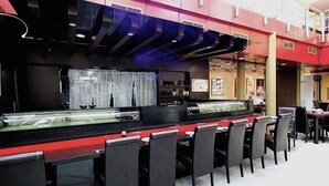 Een restaurant met een lange toonbank, zwarte stoelen en een kleurenschema van rood en zwart.