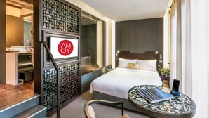 Een hotelkamer met een bed, nachtkastje, stoel en een decoratief scherm.