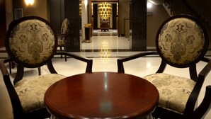 Un vestíbulo con una mesa redonda, dos sillas decorativas, una araña y una escalera.