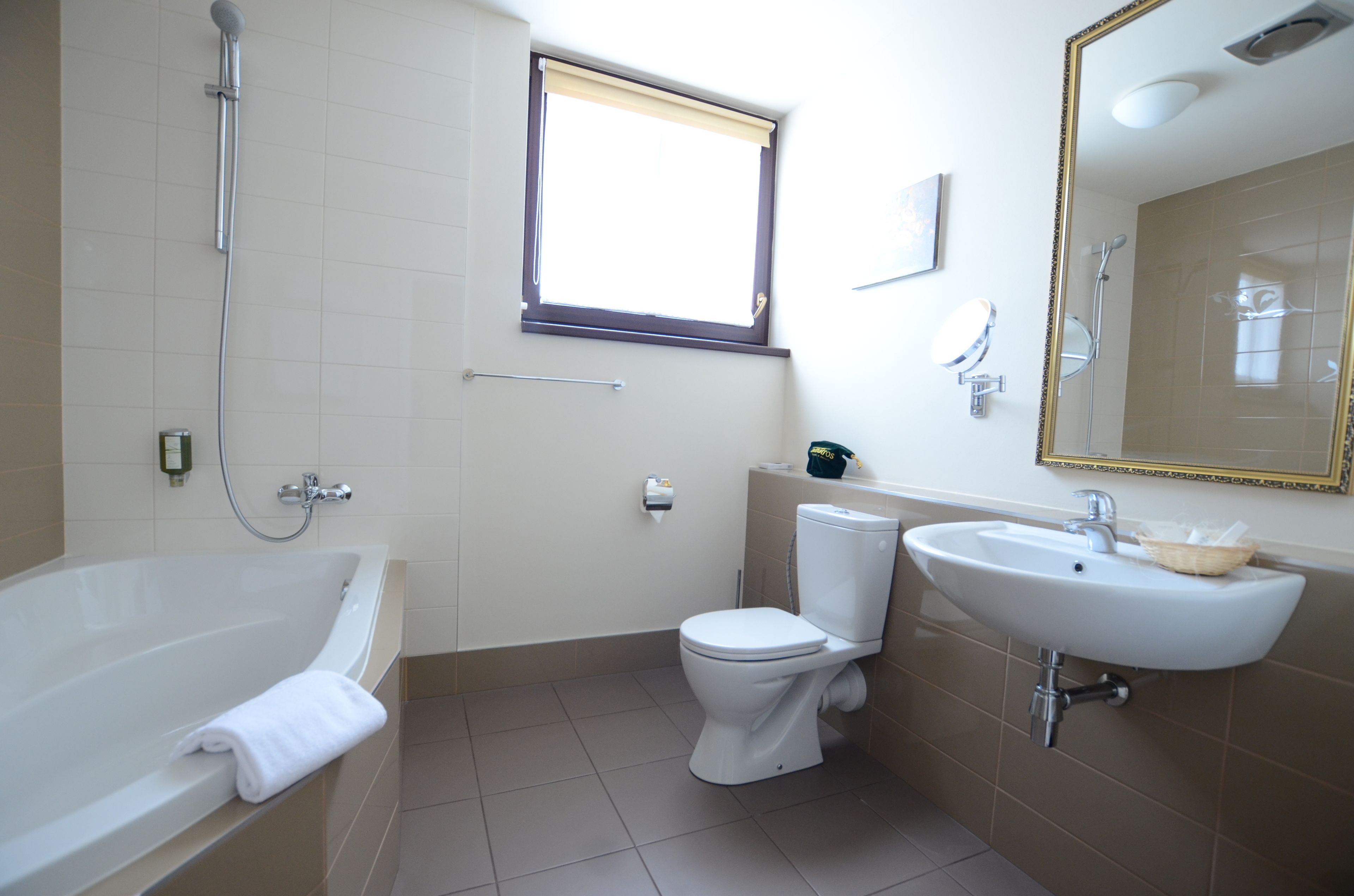 A bathroom with a bathtub, toilet, sink, and a window.