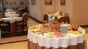 Comedor con varias mesas dispuestas para un bufé, que ofrece una variedad de alimentos y un centro de mesa floral.