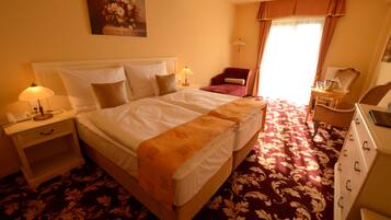 Une chambre d’hôtel avec un grand lit, une table de chevet avec une lampe, une chaise, un bureau avec une lampe et une commode.
