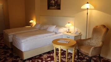 A hotel room with two beds, a round table, a chair, and two bedside lamps.