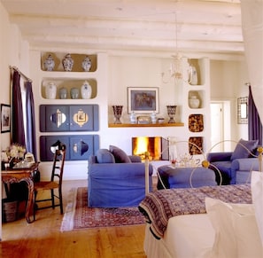A cozy living room with a fireplace, blue sofas, and decorative items on the walls.