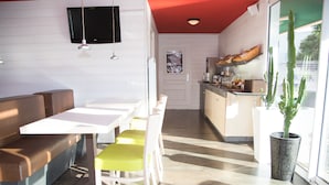 Une cuisine moderne avec un coin repas, un téléviseur fixé au mur et une plante, un cactus.