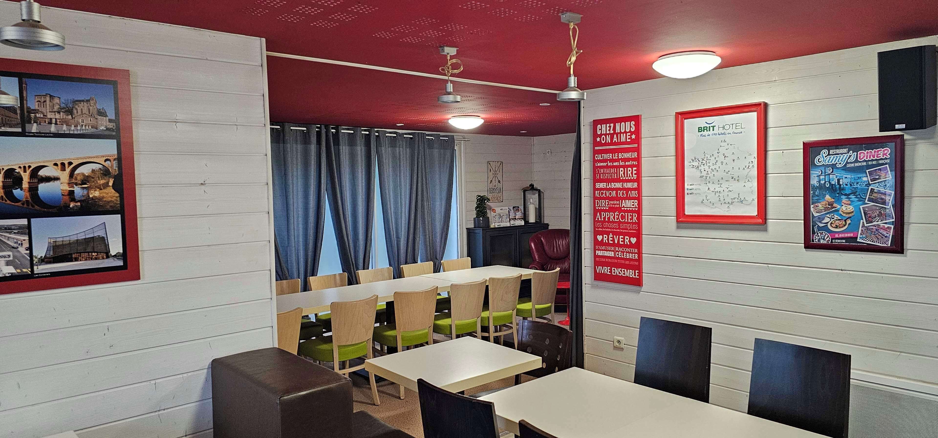 Un interno ristorante con tavoli e sedie in legno, un soffitto rosso e diverse foto incorniciate alle pareti.