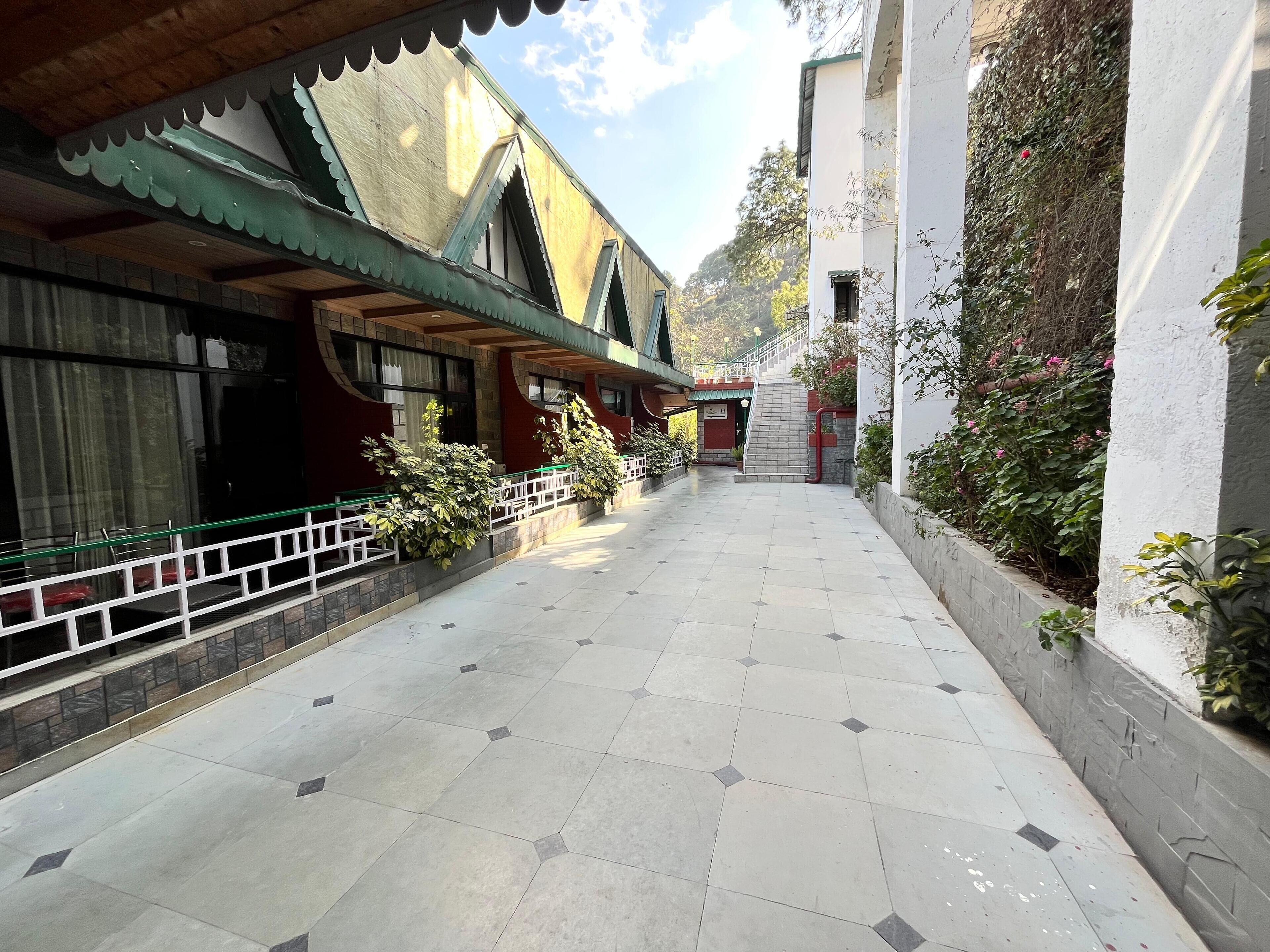 Um corredor com piso ladrilhado, escada e edifícios com fachadas verdes e vermelhas.