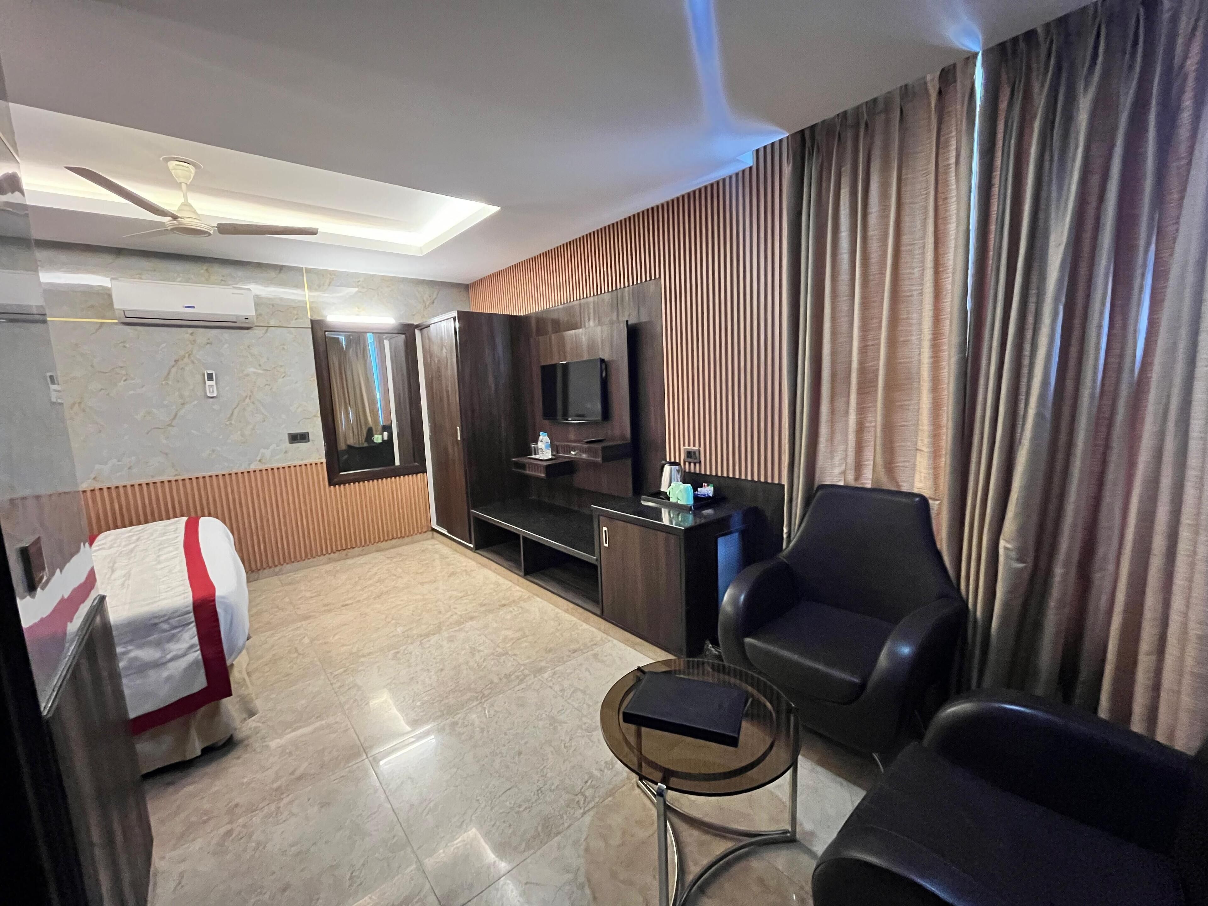 Habitació d'hotel amb llit, escriptori, cadira, televisió i ventilador de sostre.